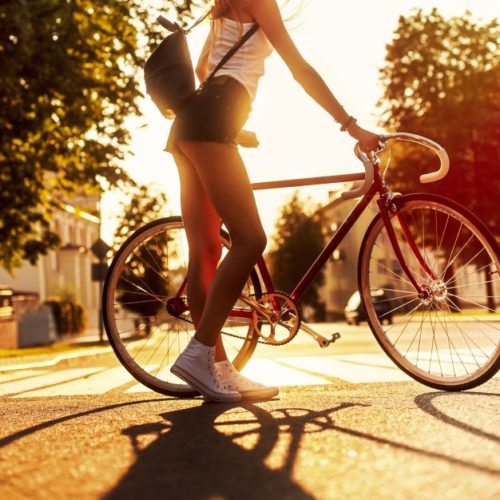 Kobieta w krótkich spodenkach trzyma rower.