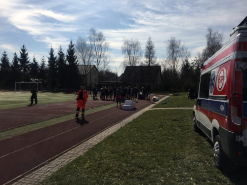 Ambulans zaparkowany obok boiska.