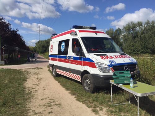 Ambulans stoi przy polnej drodze.