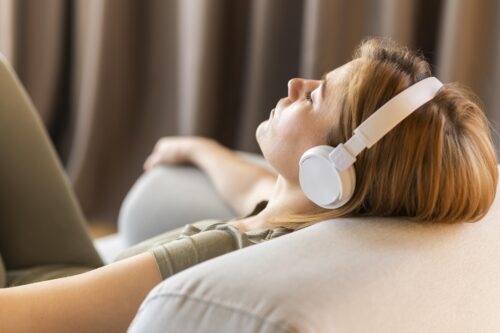 kobieta leżąca na fotelu i słuchająca muzyki na słuchawkach